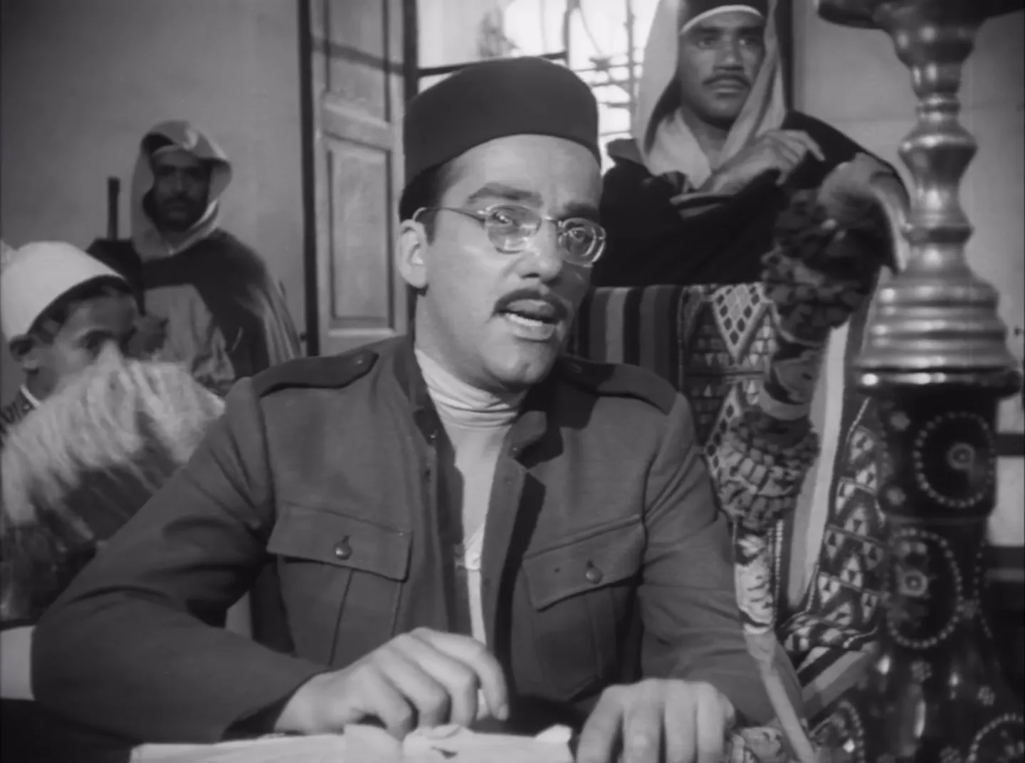 The party lands on an African beach and faces interrogation—noir stakes in a sunlit place