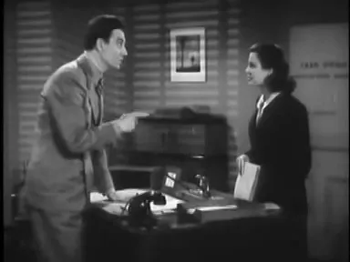 The professor questioned in a small office, the detective leans forward