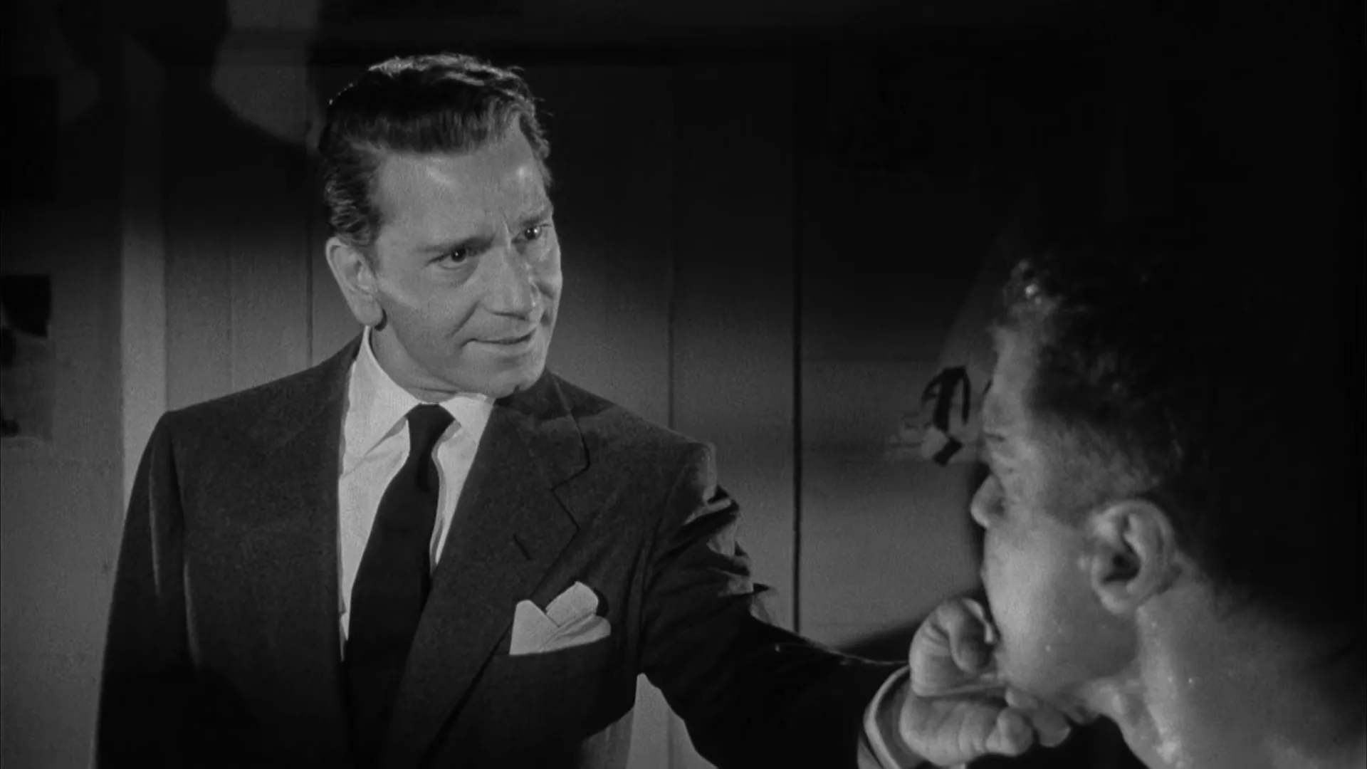 Mr. Brown lecturing Benny in a menacing, controlled manner — light falling across his face