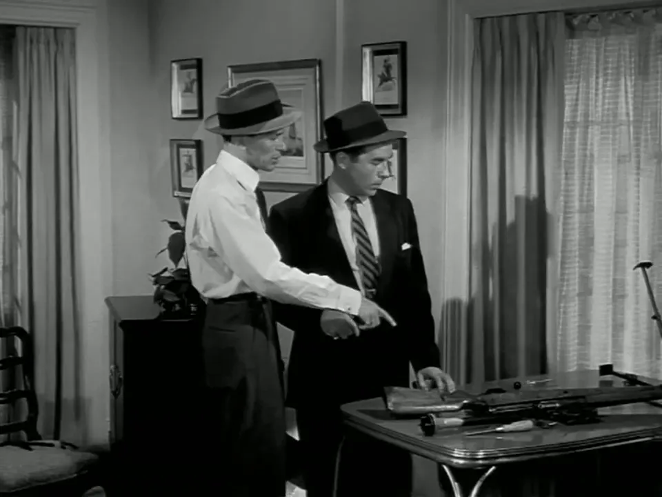 The sniper rifle bolted to the table, centered on the station track, captures the film’s grim engineering of violence
