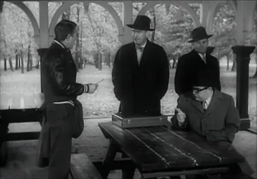 The gang deliberates and studies the bank, drawing plans and timetables