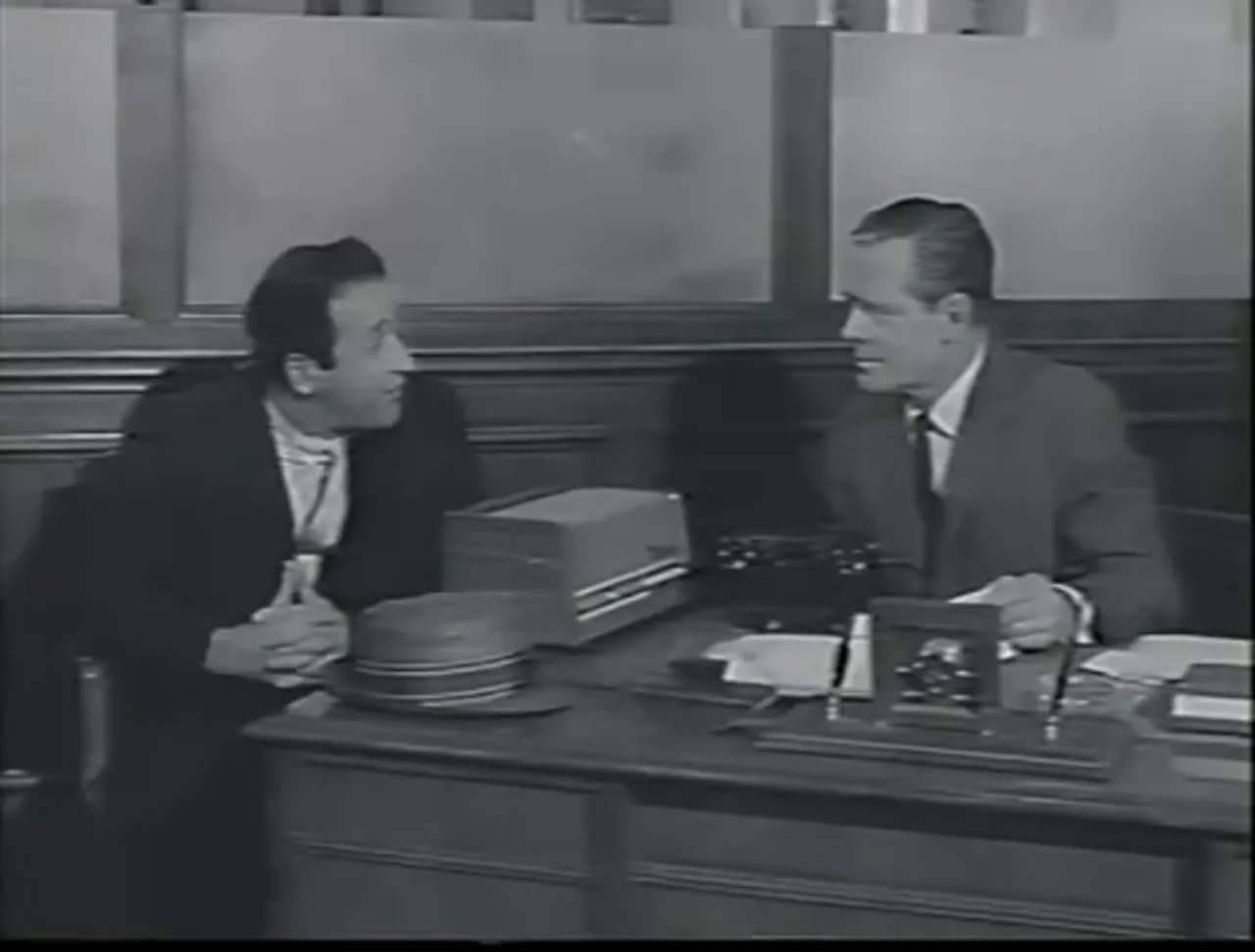 Dorella presses Ken at the bank—Tayback’s performance carries much of the film noir movie’s dramatic force.