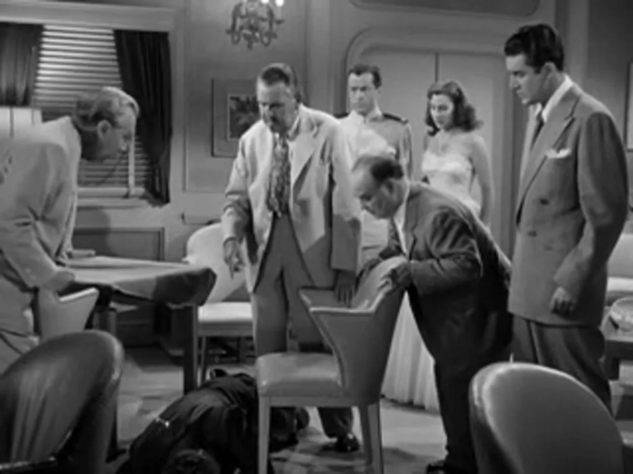 Discovery of the murdered man in the salon; onlookers clustered around the body