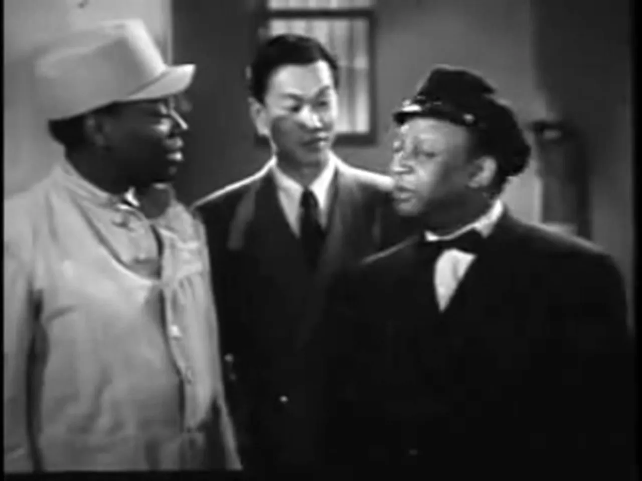 Charlie Chan and Thomas Harley in a quiet exchange behind bars; a scene charged with moral urgency.