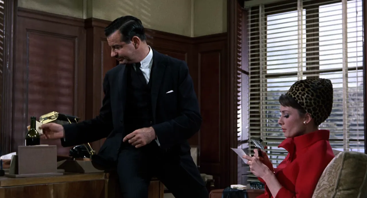 CIA administrator Bartholomew interrogates Reggie with photographs