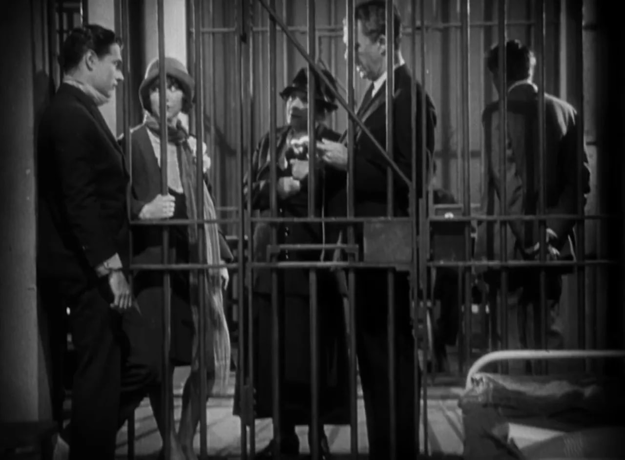Wide shot of the death‑house interior showing Bob and Ritzie at the cell bars with the warden and guards, black-and-white still