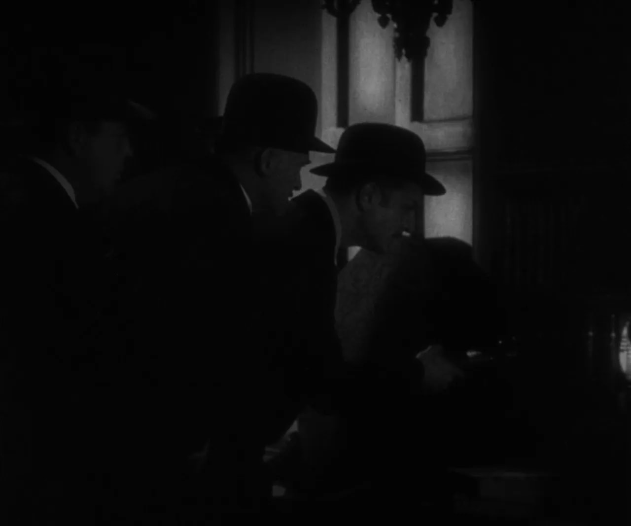 Three men in hats leaning over a table in a dimly lit library, backlit window and clear shadow detail